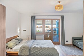 Une chambre à coucher avec un lit, un canapé, une fenêtre avec des rideaux et un luminaire au plafond.
