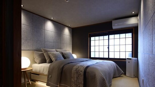 A modern bedroom with a bed, bedside table, and a large window. - Shiki Homes Ikko 9 (Kyoto)