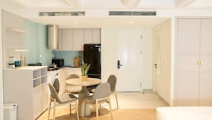 Een moderne keuken met witte kasten, een zwarte koelkast en een eethoek met een ronde tafel en vier stoelen.