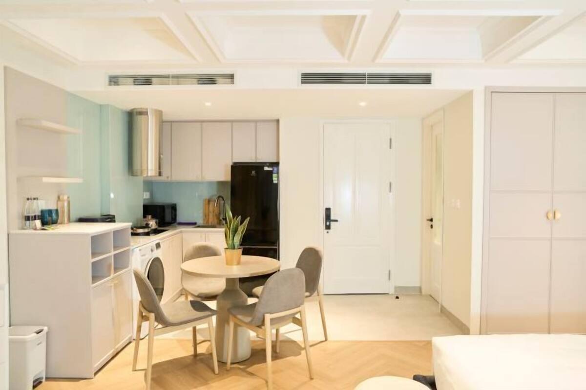 Eine moderne Küche mit weißen Schränken, einem schwarzen Kühlschrank und einem Essbereich mit einem runden Tisch und vier Stühlen.