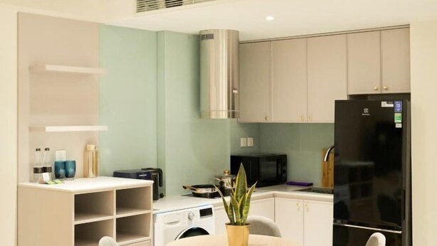 A compact kitchen with a microwave, stove, and modern appliances. - Home by La Sinfonia Tong Dan (Hanoi)