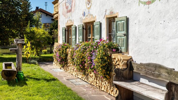 A building with a stone facade, wooden shutters, and a flower-covered wall.