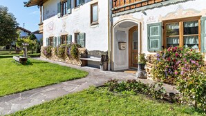 A traditional building with a stone pathway, a bench, and flower beds.