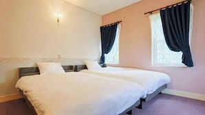 Une chambre avec deux lits, une fenêtre avec des rideaux, un luminaire fixé au mur et une moquette à motifs.
