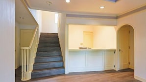 Un escalier menant à un palier avec une porte blanche et un comptoir doté d’un miroir.