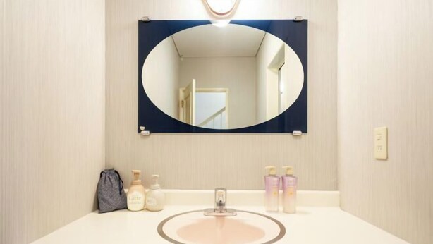 Ein Badezimmer mit einem runden Waschbecken, einem Spiegel und Toilettenartikeln auf der Ablagefläche.