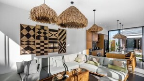 A modern living room with a sofa set, a wooden coffee table, and a dining area with a glass top table. - Villa Nature View by BaliSuperHost (Bali)