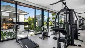 A modern gym with a treadmill, weight machines, and a rowing machine. - Villa Nature View by BaliSuperHost (Bali)