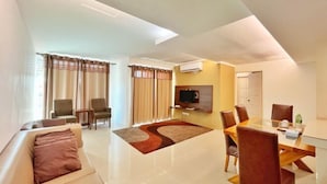 A modern living room with a sofa, chairs, a dining table, and a flat-screen TV. - Official Khalifa Suites Hotel & Apartment (Kota Bharu)