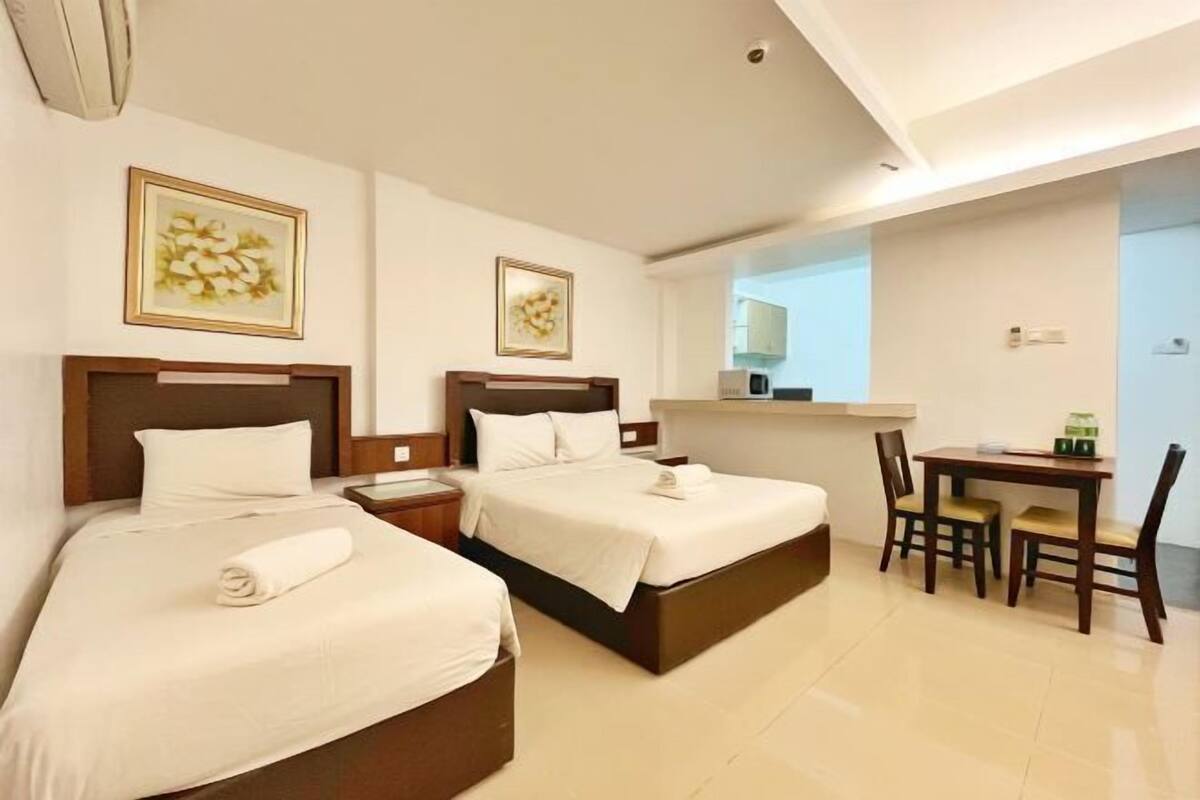 A hotel room with two beds, a desk, and chairs.