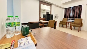 A hotel room with a wooden dining table, chairs, a TV, a fan, and a window with curtains. - Official Khalifa Suites Hotel & Apartment (Kota Bharu)