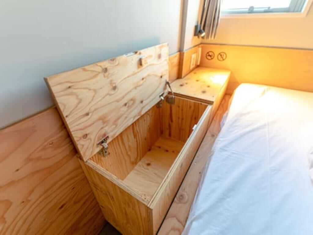 A compact wooden cabin with a bed, a small table, and a bench.