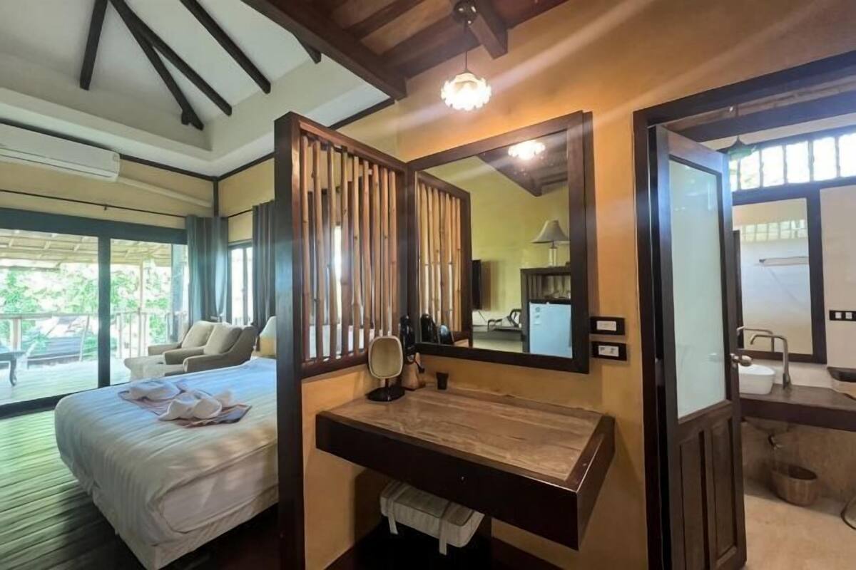 Une chambre à coucher avec un lit, un bureau, un miroir et une vue sur l’extérieur.