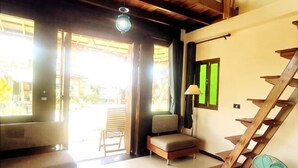 A room with a wooden staircase, a sofa, a chair, and a fan.