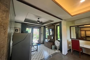 A hotel room with a ceiling fan, a desk, a chair, a mirror, and a view of the outdoors. - Relax House Lanta Old Town (Koh Lanta)
