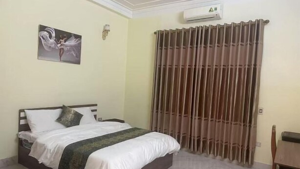 A bedroom with a bed, a painting on the wall, an air conditioning unit, and a window with curtains. - Qing Xian Homestay (Bac Ninh)