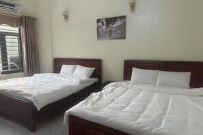 Two single beds with wooden headboards in a room with a window and a wall-mounted light fixture. - Qing Xian Homestay (Bac Ninh)