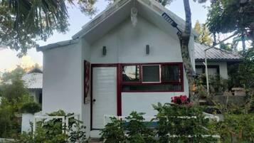 Un pequeño edificio de una sola planta con fachada blanca y un marco de ventana rojo.