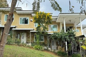 A residential building with multiple balconies, a well-maintained lawn, and a variety of plants. - Kookie’s Place Homestay (Mae Rim)