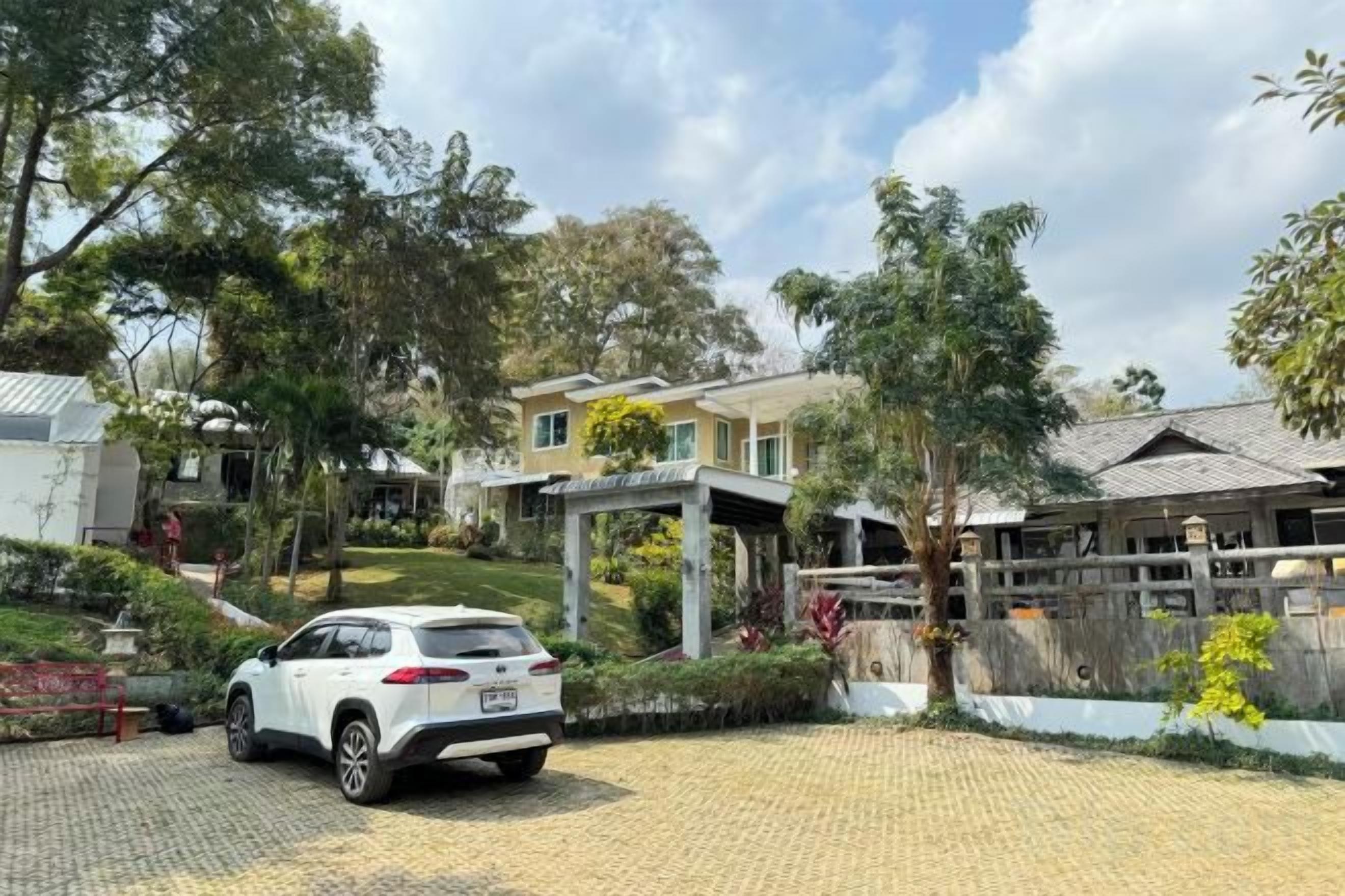 A residential property with a paved driveway, a white car parked, and a covered outdoor area.