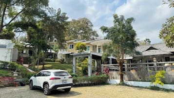 A residential property with a paved driveway, a white car parked, and a covered outdoor area.