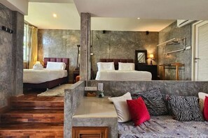 Une chambre d’hôtel avec deux lits, un canapé, un escalier en bois et un mur en pierre.