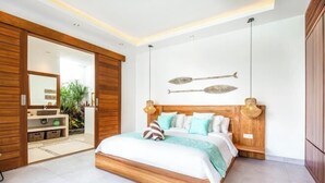 A modern bedroom with a wooden bed frame, a large mirror, and two decorative fish mounted on the wall. - Canggu CAROLE · (Bali)