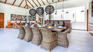 A spacious dining area with a long table, wicker chairs, and hanging pendant lights. - Canggu CAROLE · (Bali)