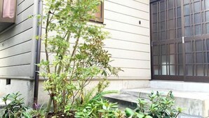 Un immeuble résidentiel doté d’un portail de garage, d’un petit jardin avec différentes plantes et d’une fenêtre donnant sur le jardin.