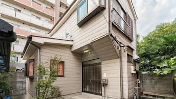 A residential building with a sloped roof, a gated entrance, and a small garden area.