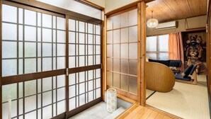 Une pièce de style japonais traditionnel, avec des portes coulissantes, un sol recouvert de tatamis et un plafond bas en bois.