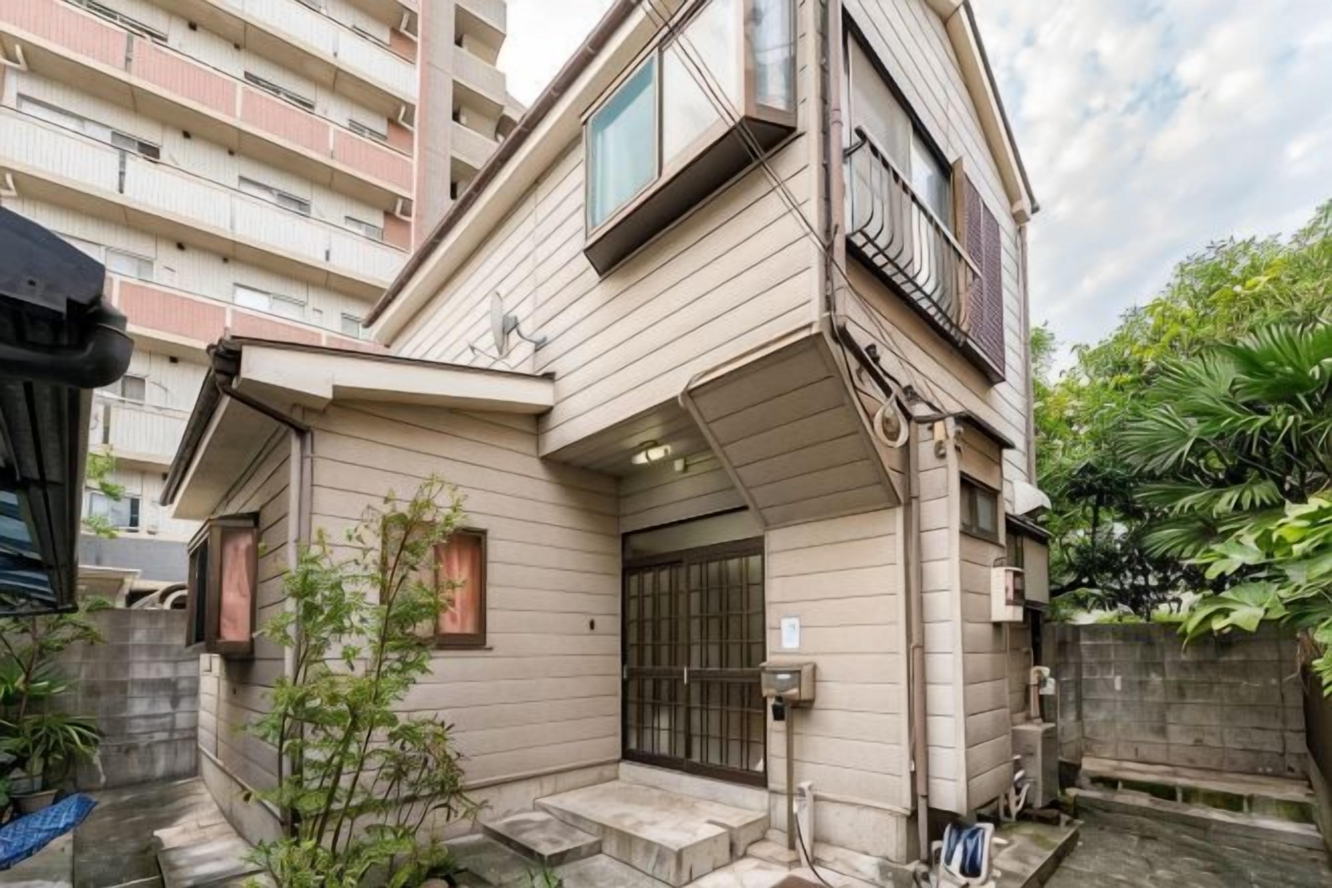 A residential building with a sloped roof, a gated entrance, and a small garden area.