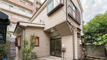 A residential building with a sloped roof, a gated entrance, and a small garden area.