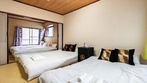 Une chambre d’hôtel avec deux lits, un plafond en bois et une porte coulissante donnant sur un balcon.