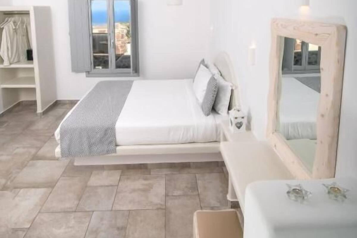 Ein Schlafzimmer mit Bett, Kleiderschrank, Fenster und Spiegel.