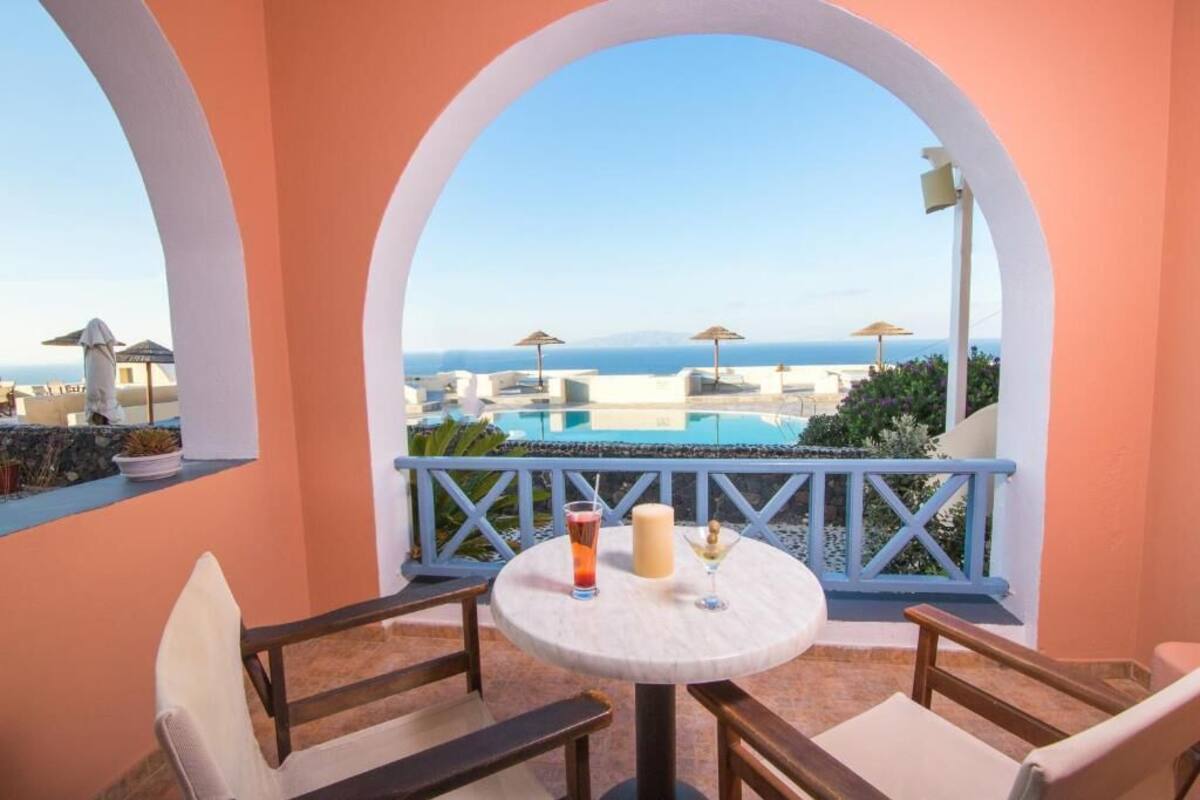 Ein Balkon mit Tisch, Stühlen und Blick auf das Meer und die Bebauung.