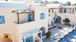 Un patio con una pérgola, zona de estar y plantas en macetas.