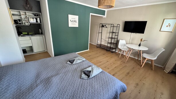 Une chambre d’hôtel moderne équipée d’un lit, d’un petit bureau, d’une télévision et d’un coin salon.