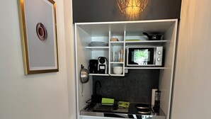 Une cuisine compacte avec des meubles blancs, un four à micro-ondes encastré et un luminaire suspendu.