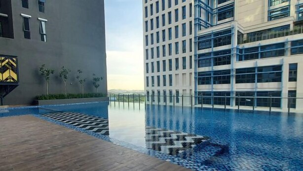 A modern building with a rooftop infinity pool, surrounded by a wooden deck and small plants. - Shahdila @ Alinea (Shah Alam)