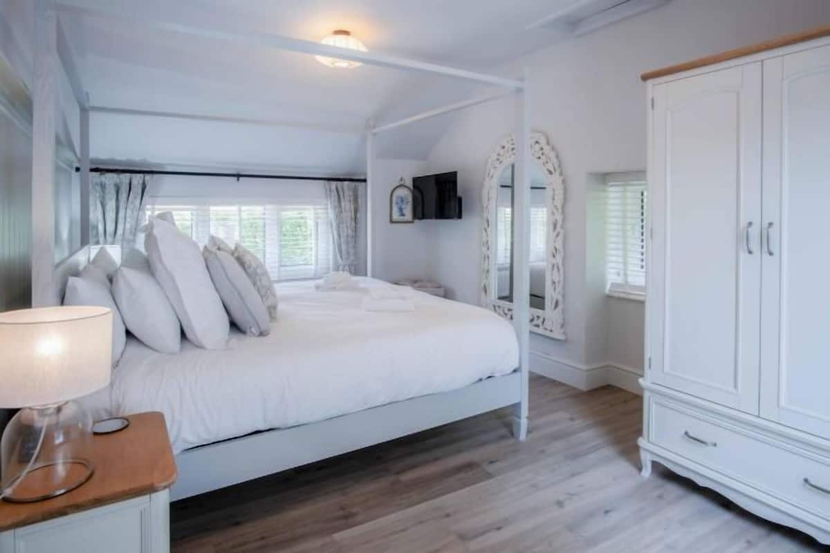 A bedroom with a bed, a nightstand, a wardrobe, and a mirror.