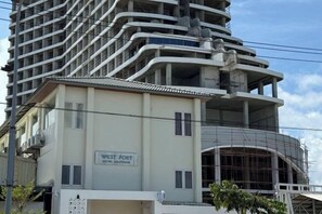 A hotel with a sign reading "West Port Hotel Boutique" and a modern, multi-story building with a curved facade. - Westport Hotel Boutique (Sihanoukville)