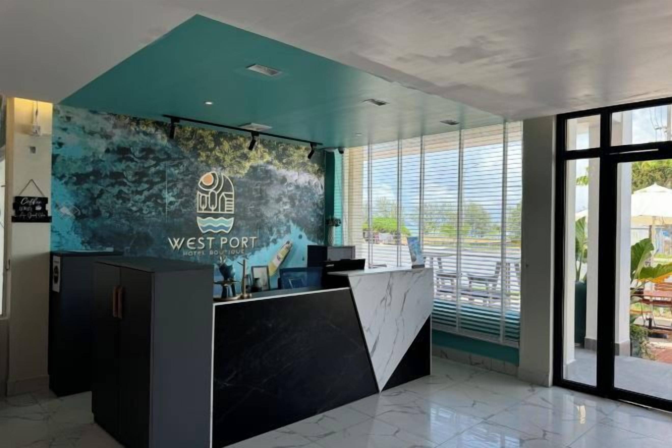 Un mostrador de recepción con un logotipo, una decoración interior moderna y ventanas amplias.