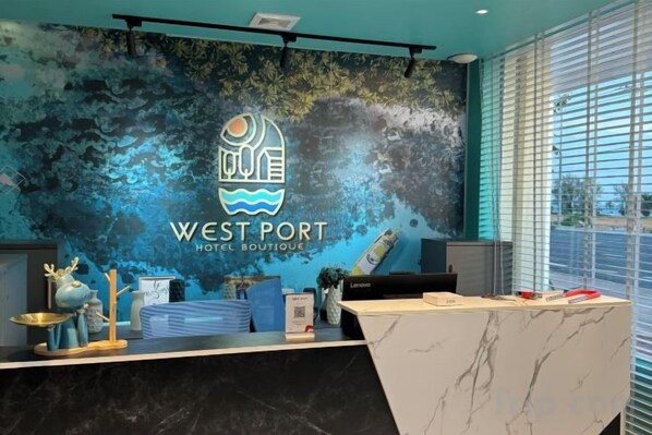 A hotel reception desk with a logo, a marble counter, and a window with blinds. - Westport Hotel Boutique (Sihanoukville)