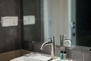 A modern bathroom with a large mirror, a chrome faucet, and toiletries on the counter. - Westport Hotel Boutique (Sihanoukville)