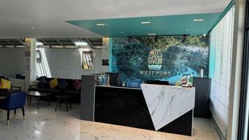 A reception desk with a logo, a seating area with chairs, and a large window.