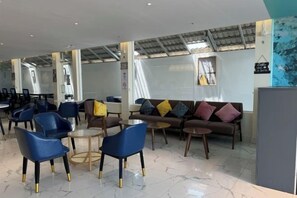 A modern lounge area with seating arrangements, including sofas and chairs, and a high ceiling with skylights. - Westport Hotel Boutique (Sihanoukville)