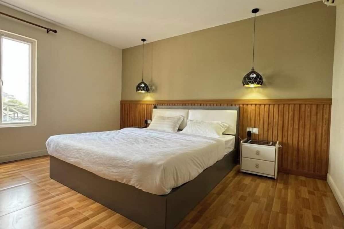 A bedroom with a bed, bedside tables, and pendant lights.