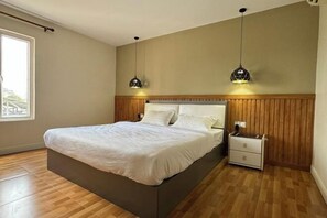 A bedroom with a bed, bedside tables, and pendant lights. - Westport Hotel Boutique (Sihanoukville)