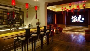 A modern bar area with a wooden floor, red lanterns, and a bar counter with stools. - Purana Residence (Koh Samui)